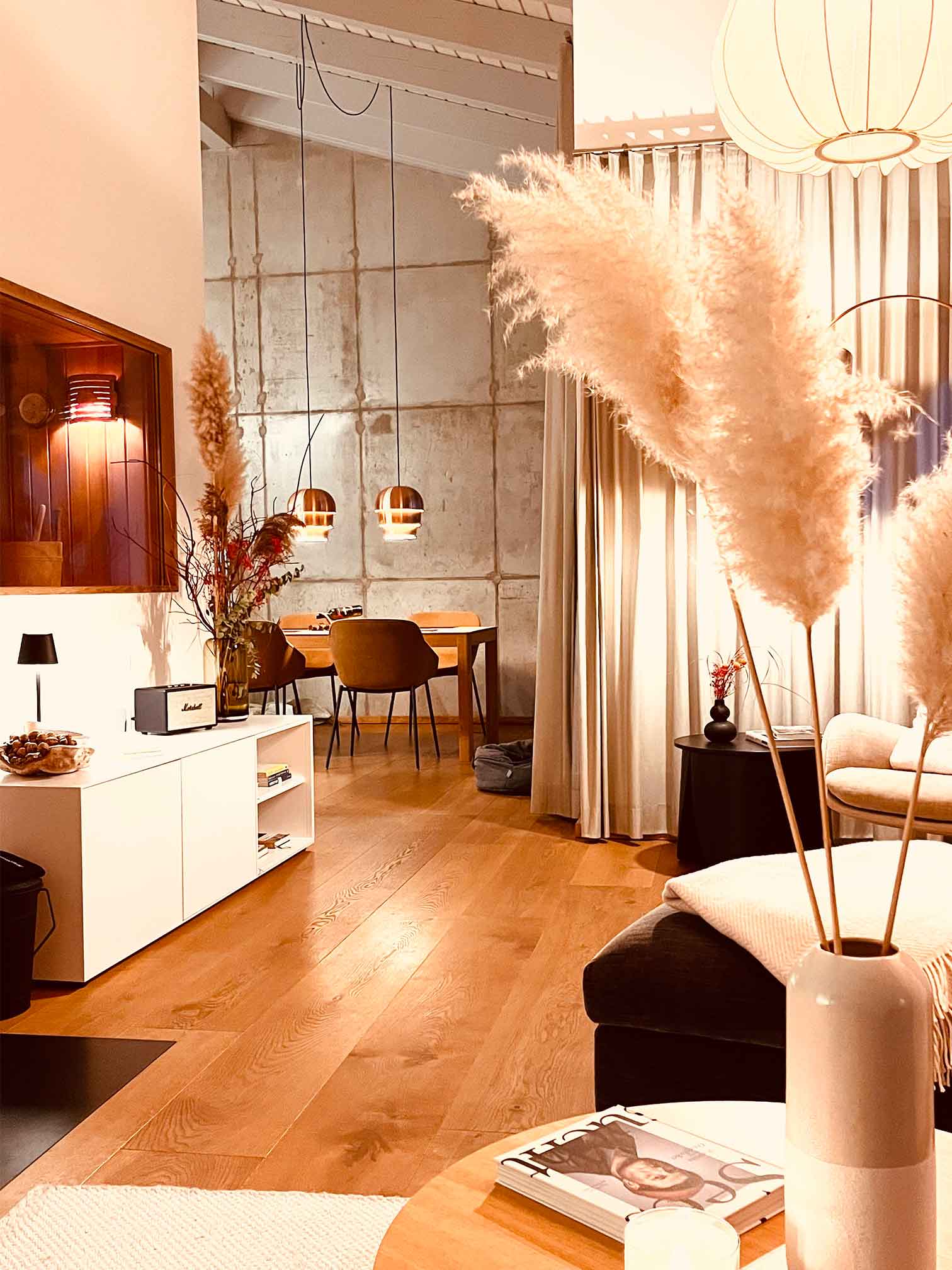 Stimmungsvoll beleuchteter Wohnbereich der Ferienwohnung FISCHER:IN mit Kerzen, Designmöbeln und warmem Holz – ideal für ruhige Wintertage auf Ummanz.